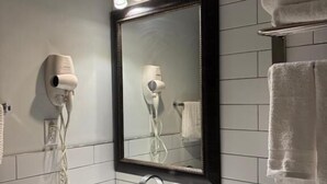 A bathroom with a white sink, a mirror, and a towel rack. - Lantern City Suites (Toronto)