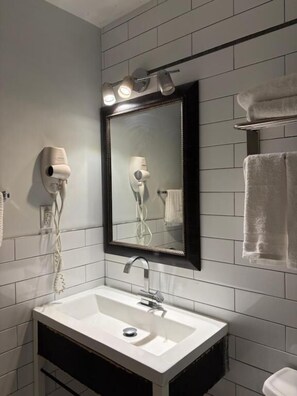 Een badkamer met een witte wastafel, een spiegel en een handdoekrek.