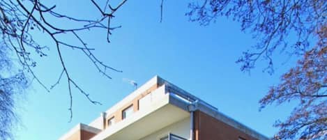 A multi-story building with a flat roof, balconies, and a brick facade.
