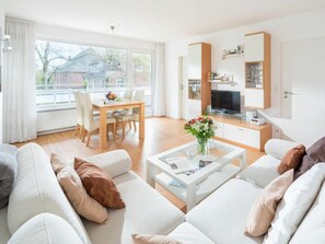 A modern living room with a sofa set, a dining table, and a television. - Holiday Apartment in Norderney With Wi-fi (Norderney)