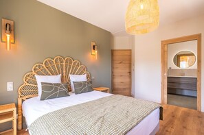 A bedroom with a large bed, a wooden headboard, bedside lamps, a hanging light fixture, and a door leading to a bathroom. - Comfortable Villa in Saint-remy-de-provence (St.-Rémy-de-Provence)