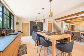 A modern kitchen with a central island, pendant lighting, and a dining area with chairs and a table. - Comfortable Villa in Saint-remy-de-provence (St.-Rémy-de-Provence)
