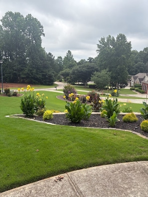 A residential area with a well-maintained lawn, flower beds, and a curved driveway.