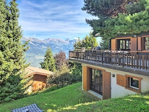 Ein modernes Chalet mit einem Balkon mit Blick auf eine gebirgige Landschaft.