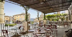 An outdoor dining area with tables and chairs, overlooking a town with historic buildings. - Peaceful Villa Haven in the Luberon (Beaumettes)