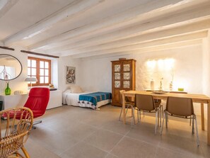 A room with a bed, a dining table with chairs, a red chair, a cabinet, and a wall-mounted lamp. - Finca Santa Catalina · 3 casitas · Private plunge pool (La Guancha)