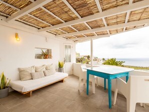Ein Zimmer mit einem weißen Sofa, einem blauen Tisch und Blick aufs Meer.