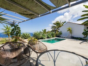 Ein Poolbereich mit Liegestühlen und Blick auf das Meer.