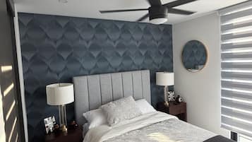 Een moderne slaapkamer met een bed, twee nachtkastjes, een plafondventilator en een raam met zonwering.