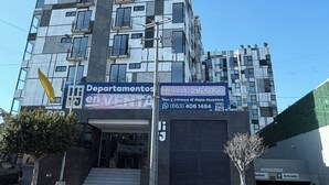 Un immeuble à plusieurs étages avec une enseigne indiquant « Appartements à vendre » et les coordonnées.