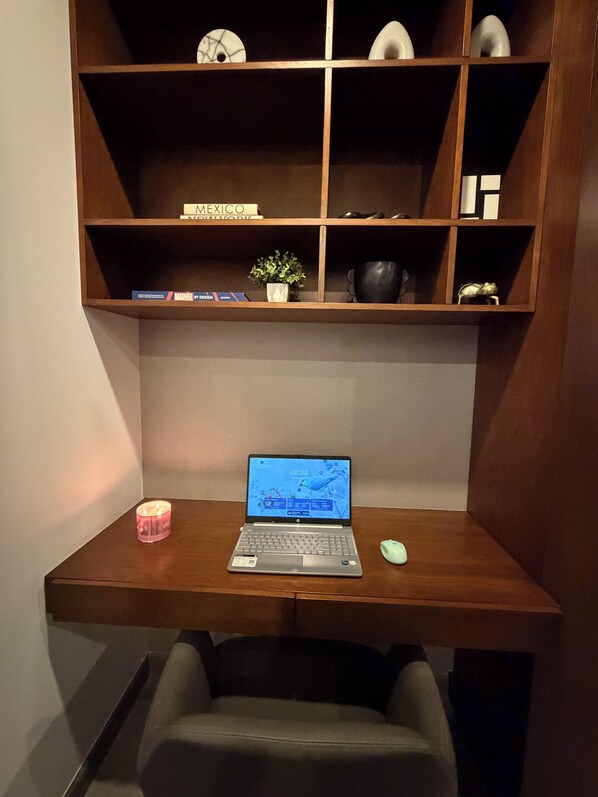 Ein Holztisch mit einem Laptop, einer kleinen Topfpflanze und einer Kerze.