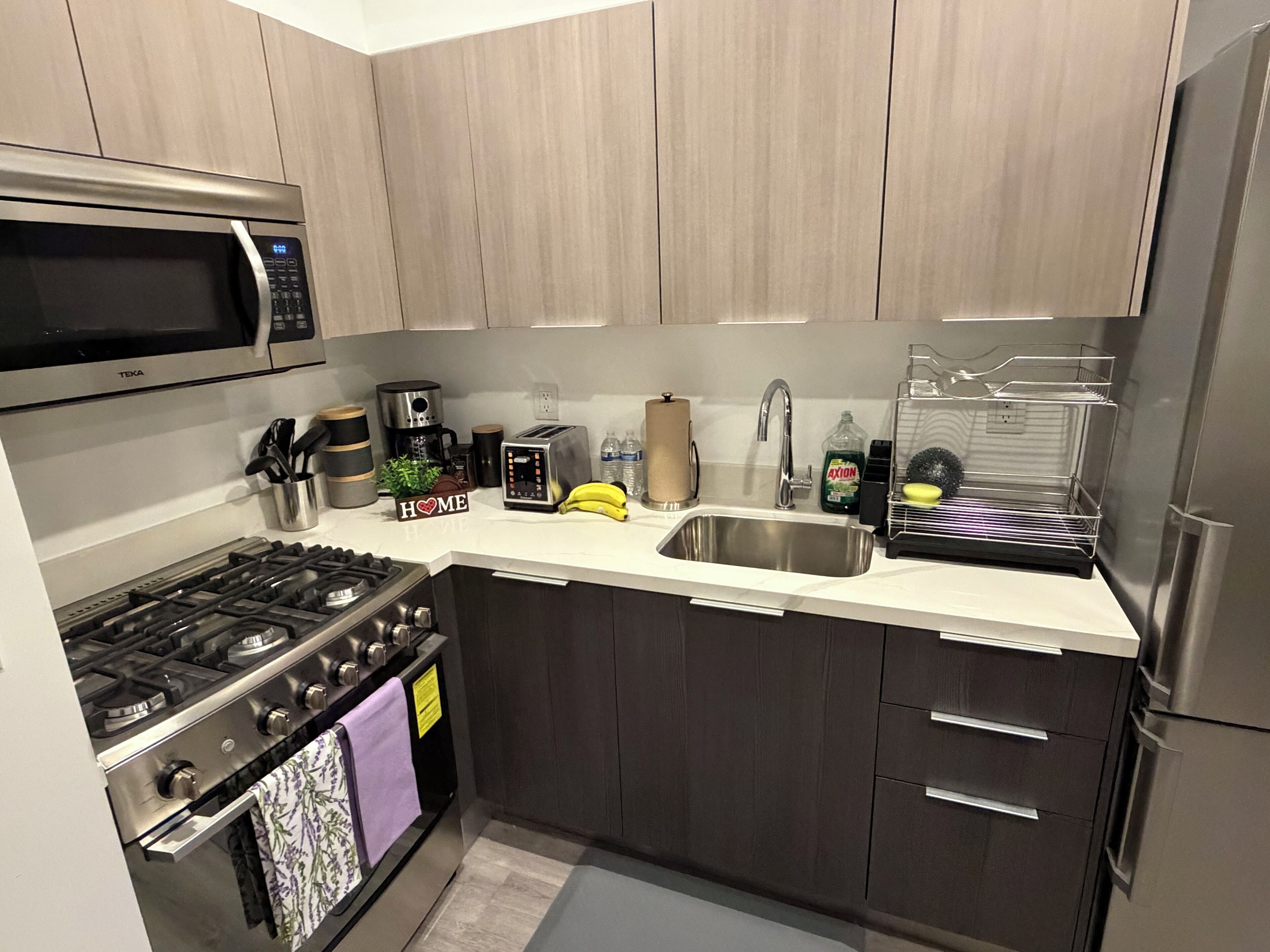 Een moderne keuken met roestvrijstalen apparatuur, een magnetron, een koffiezetapparaat en een broodrooster.