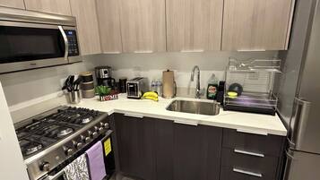Een moderne keuken met roestvrijstalen apparatuur, een magnetron, een koffiezetapparaat en een broodrooster.