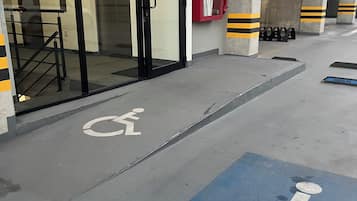 A building entrance with a glass door, a wheelchair accessibility sign, and a fire extinguisher.