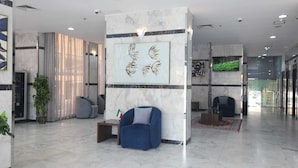 A lobby with marble flooring, seating areas, and artwork on the walls. - Atlantis Hotel Suite & Apartment (Salmiya)