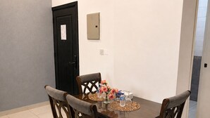 A dining area with a rectangular table, four chairs, and a decorative centerpiece. - Atlantis Hotel Suite & Apartment (Salmiya)