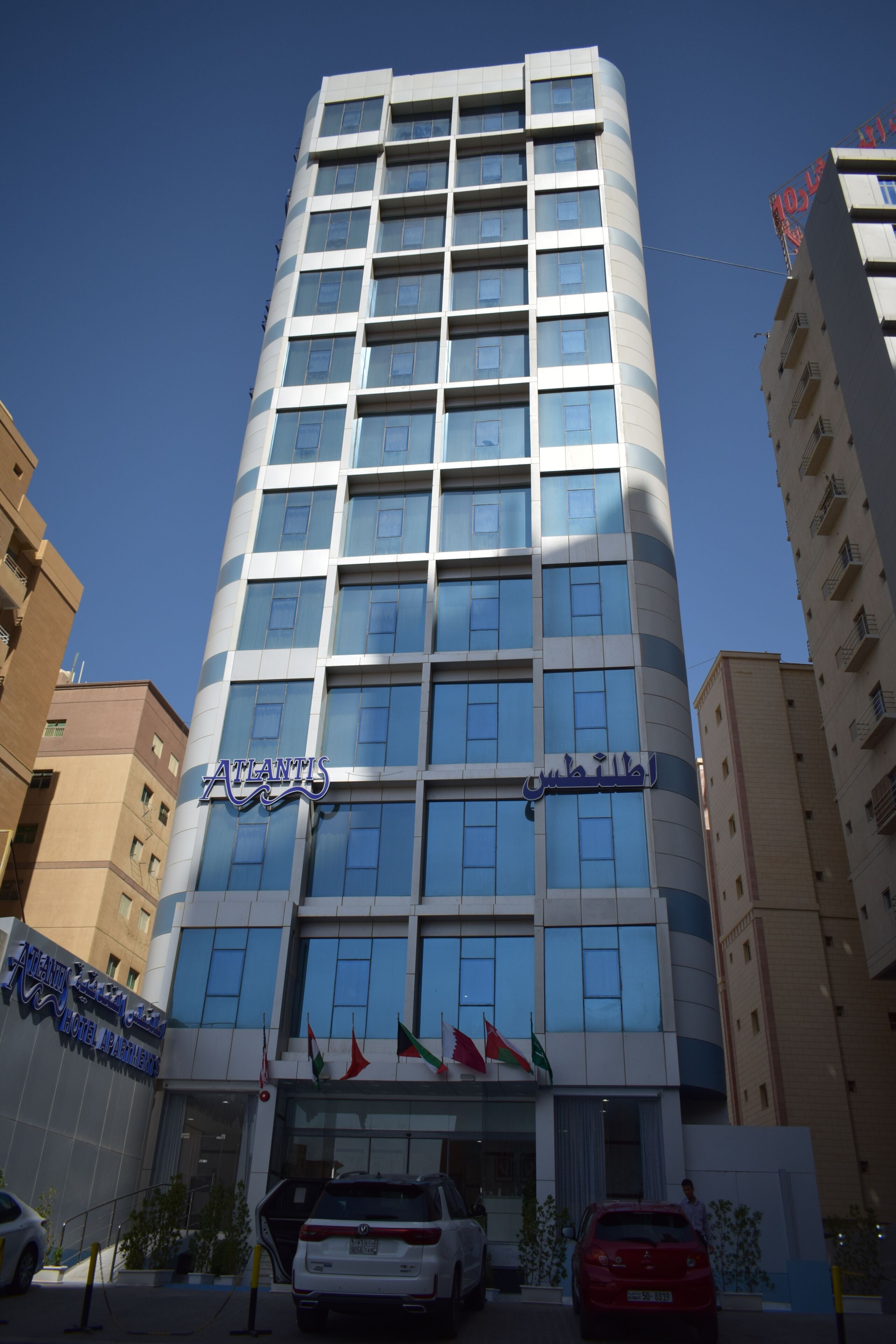 Un edificio de apartamentos hotel con varias plantas, fachada moderna, ventanas grandes y un cartel que indica que es Atlantis Hotel Apartments.