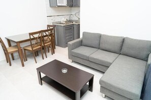Ein modernes Wohnzimmer mit einem grauen Sofa, einem Holzespeisetisch mit Stühlen und einem dunkelgrauen Couchtisch.