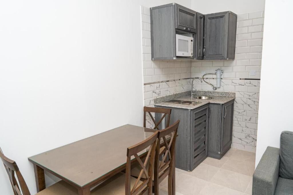 A compact kitchen with a microwave, sink, and cabinets.