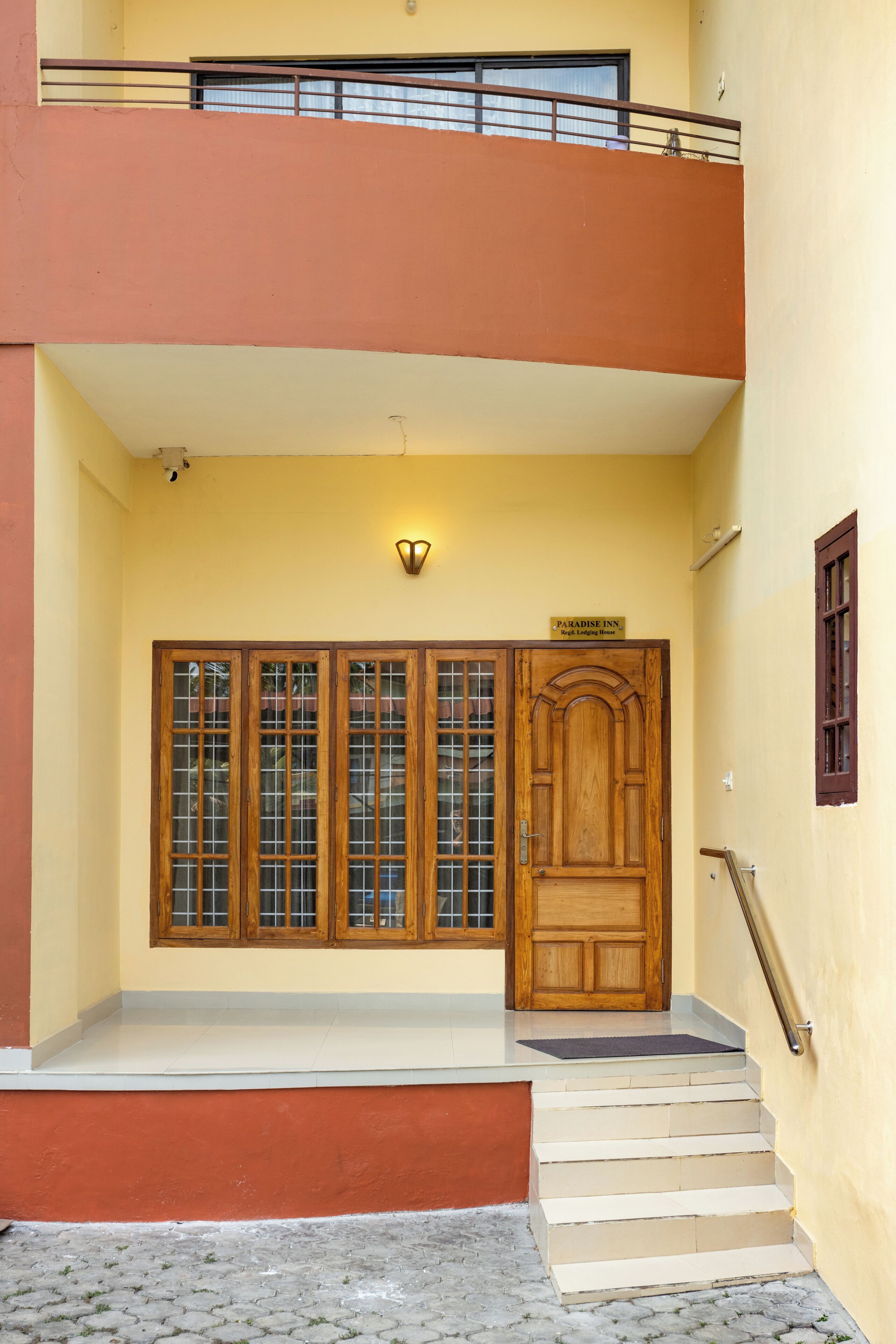 A building entrance with a wooden door, a balcony, and a staircase leading to the entrance.