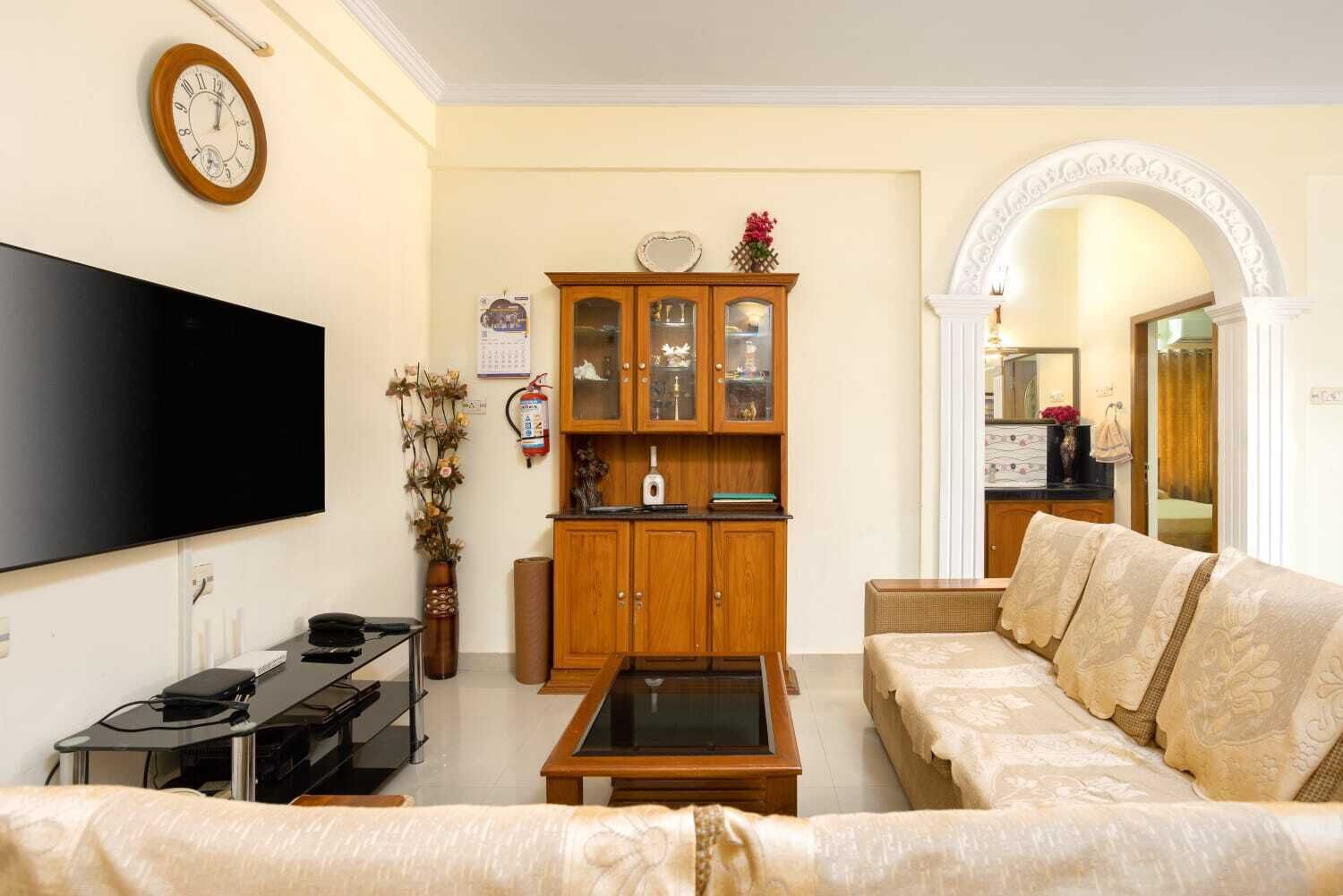 Un salon comprenant un téléviseur à écran plat, un meuble en bois avec des portes en verre, un canapé et une table basse.