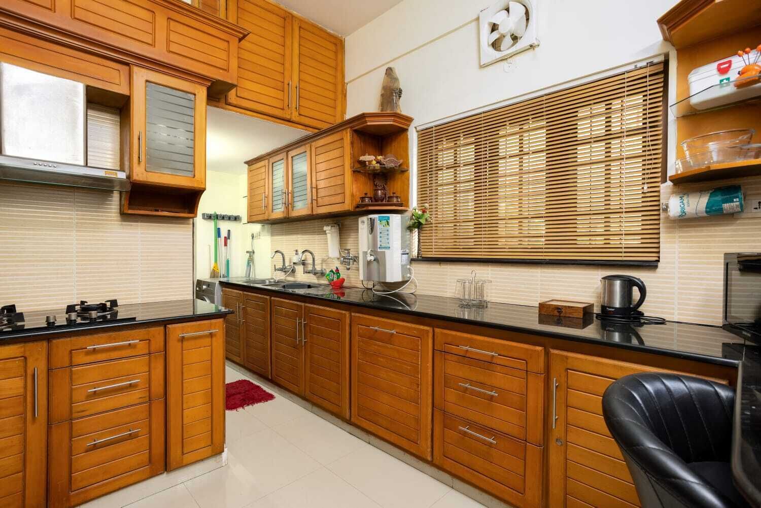 A kitchen with wooden cabinets, a sink, a stove, and a window with blinds.
