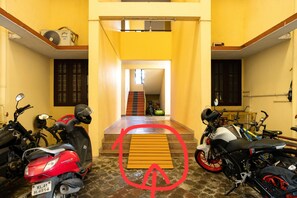 A motorcycle garage with multiple bikes, a staircase leading to an upper level, and a yellow wall.