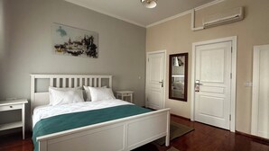 Quarto com cama, mesas de cabeceira, espelho e porta.