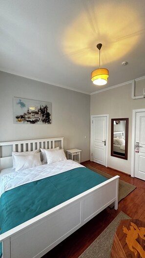 A bedroom with a bed, a bedside table, a nightstand, a wall-mounted mirror, and a ceiling light fixture. - Ihlamur Suit Otel (Beşiktaş)