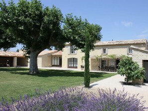 A two-story building with a tiled roof, a paved courtyard, and a tree in the foreground. - Private Pool Stay in Heart of Luberon (Lagnes)