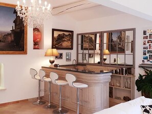 Eine moderne Küche mit Barbereich, Barhocker, einer Kandelaber und Kunstwerken an den Wänden.