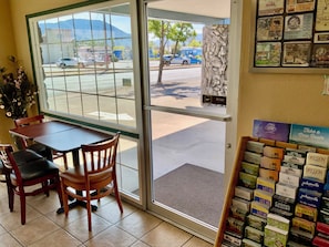 L’intérieur d’un restaurant, avec une table et des chaises, un présentoir rempli de brochures de voyage et une vue sur la rue.