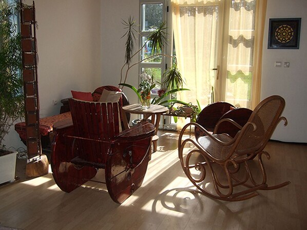 Une pièce avec un fauteuil à bascule, une table en bois et une plante en pot.