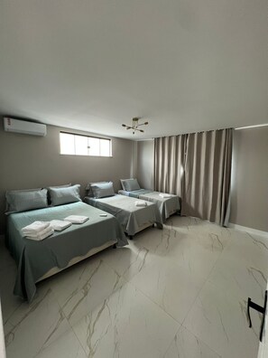 A hotel room with two beds, a window, a ceiling fan, and a curtain. - Modern Ocean View Villa with Private Pool (Ilhéus)