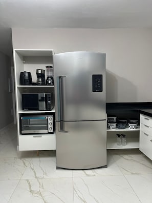 A kitchen with a stainless steel refrigerator, a microwave, a toaster oven, and a coffee maker on a white cabinet. - Modern Ocean View Villa with Private Pool (Ilhéus)