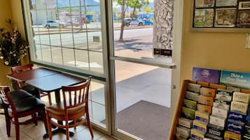 A restaurant interior with a table and chairs, a display of travel brochures, and a view of the street outside.