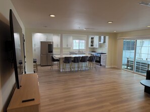A modern kitchen with white cabinets, a stainless steel refrigerator, and a bar area with stools. - 3-bedroom house in perfect Los Angeles with cool AC and pool (Los Angeles)