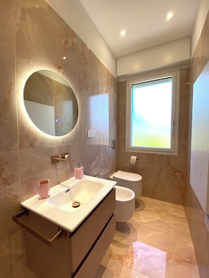 Ein modernes Badezimmer mit Waschtisch, Toilette und großem Spiegel.