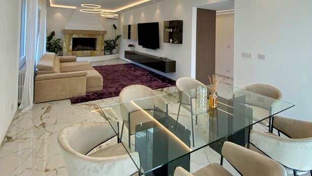A modern living room with a glass dining table, comfortable seating, a fireplace, and a large TV. - Vrbo Property (Castel Bolognese)
