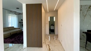 A modern interior with a marble floor, a sofa, and a dining area.