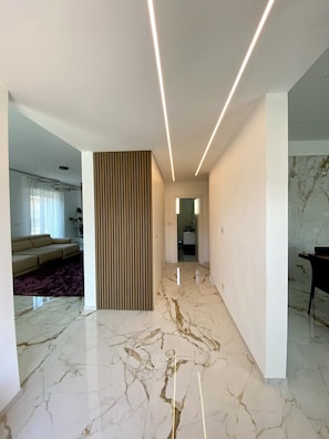 Un interior moderno con suelo de mármol, un sofá y una zona de comedor.