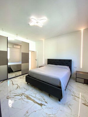 A modern bedroom with a large bed, a built-in wardrobe, and a mirror.