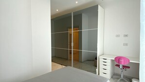 A modern bedroom with a bed, a desk with a chair, a wardrobe, and a mirror. - Vrbo Property (Castel Bolognese)