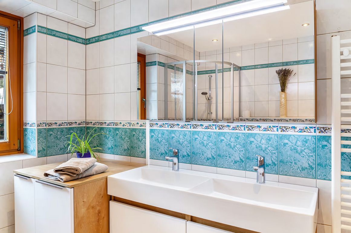 Un baño moderno con un espejo grande, dos lavamanos y una zona de ducha.