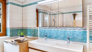 Un baño moderno con un espejo grande, dos lavamanos y una zona de ducha.