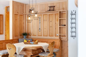 A wooden-paneled room with a dining table, chairs, and hanging light fixtures.