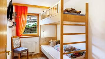 A bunk bed room with a window, a chair, and a radiator.