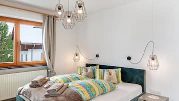 A bedroom with a bed, bedside tables, and a window.