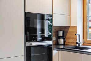 Una cocina moderna con horno empotrado, cafetera y pileta de acero inoxidable.