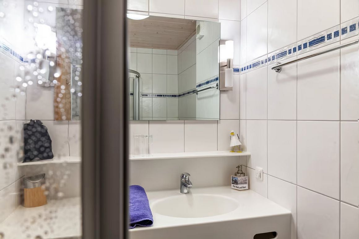 A bathroom with a white sink, a mirror, and a shower area.